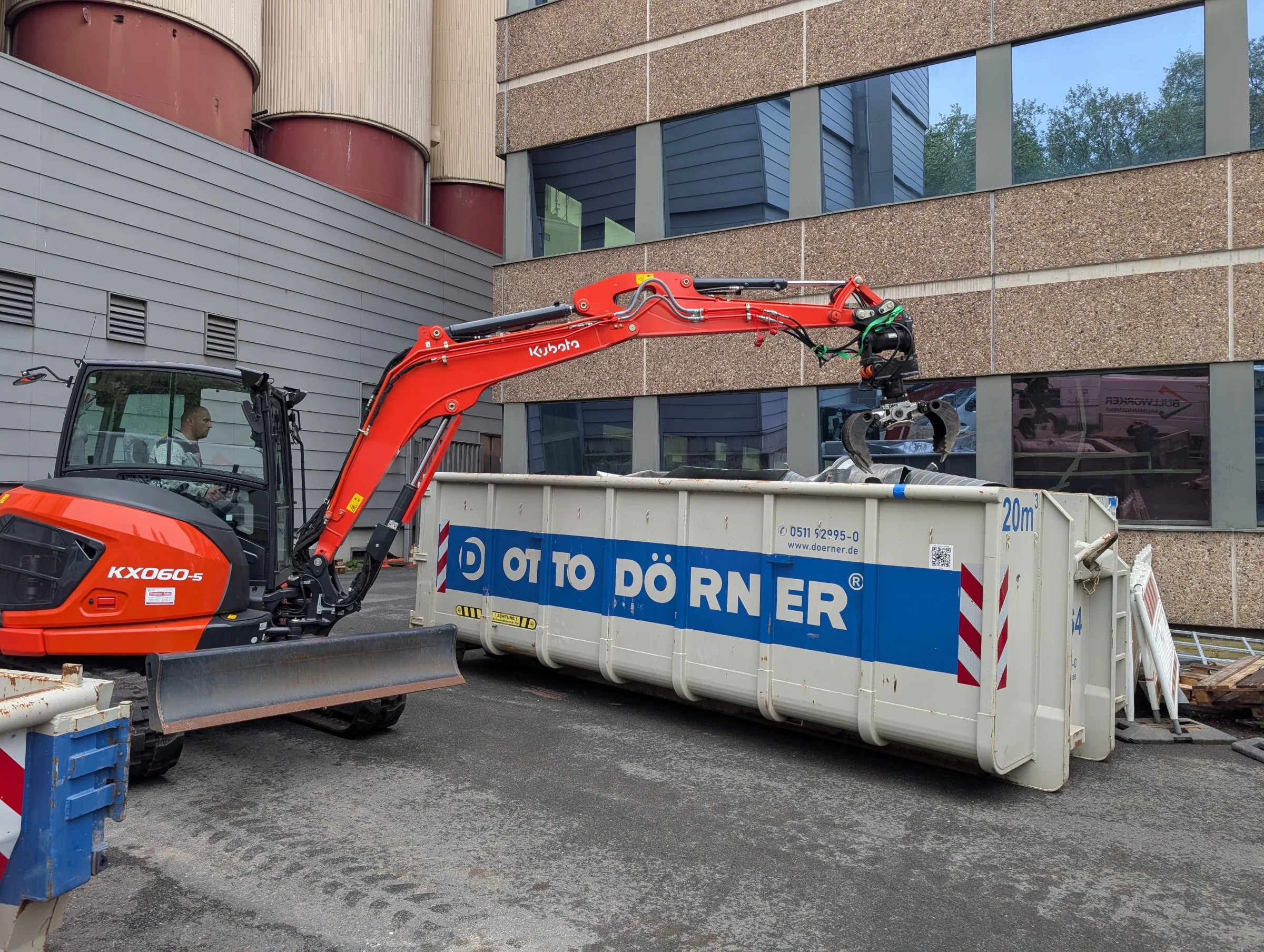 Roter Kubota-Bagger mit Container von Otto Doerner auf urbaner Baustelle